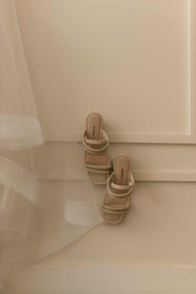 Classy beige high-heel shoes against a minimalist wall, exuding elegance and simplicity.